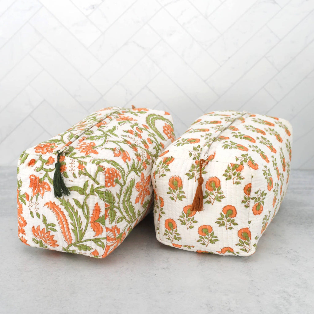 Two floral-patterned quilted travel toiletry cases on a light gray surface with a white quilted background