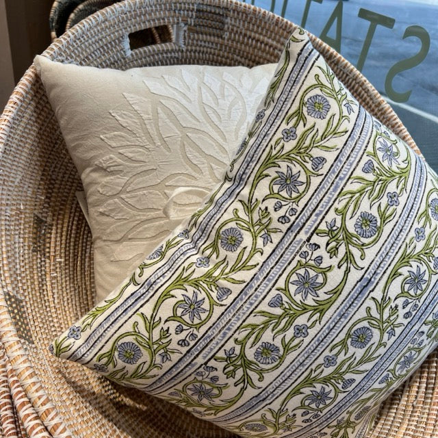 Giant floor hold-all Oval shaped Woven baskets with pillows in the shop window at Hill Station. In the basket are two Decorative pillows, one white, one with floral patterns.