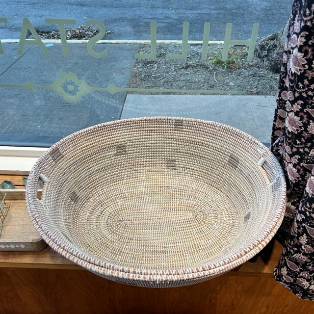 Giant floor hold-all Oval shaped Woven baskets with pillows in the shop window at Hill Station. Two same-sized baskets are nested in each other