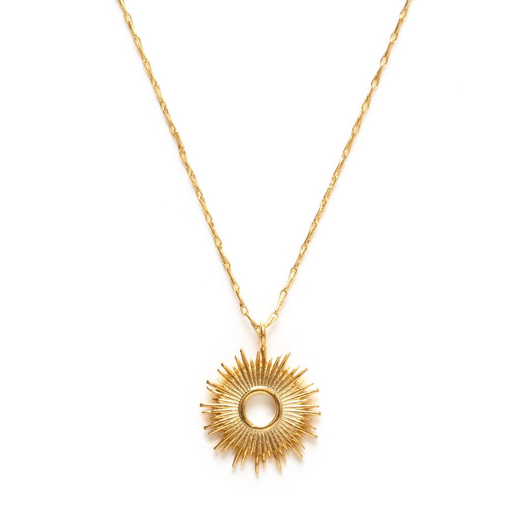 Gold sunburst pendant necklace on delicate chain against a white background.