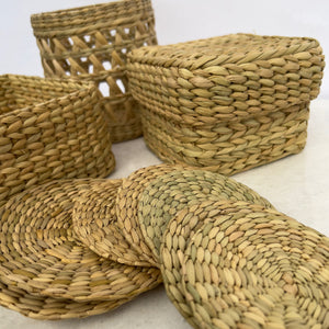 Grouping of traditional weaving from northeastern India. Open weave basket, square basket, box with lid, and coasters.
